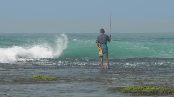 Aged Sinhalese Man Stands in Endless Blue Sea Water with Rod