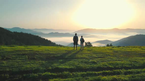 A Man and a Woman on Top of a Mountain Meet the Sunrise