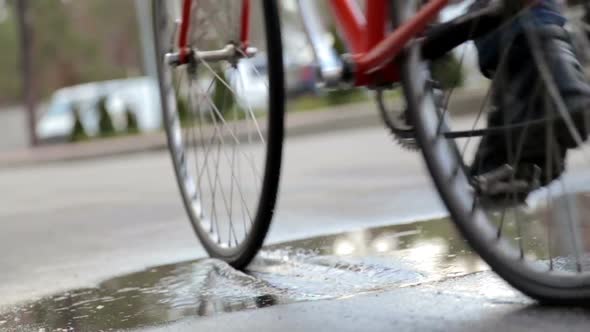 A Cyclist Rides Through a Puddle