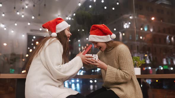 The Girl Gives a Gift to Her Female Friend in Caffe