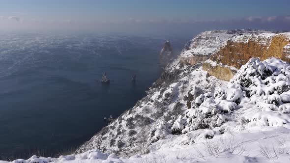 Snow Covered Rocky Cliffs Over Sea