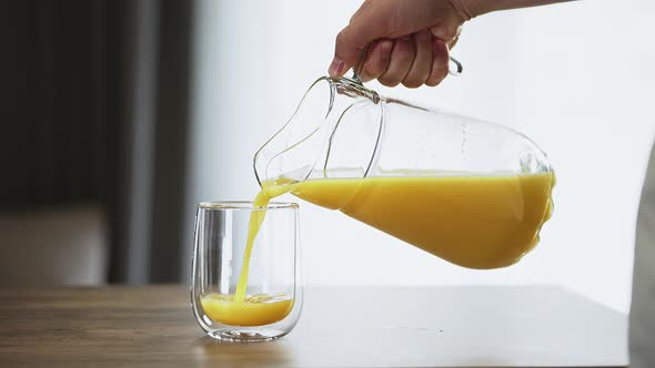 man pours orange juice into a glass. simple nutritious breakfast. quench your thirst with a refresh