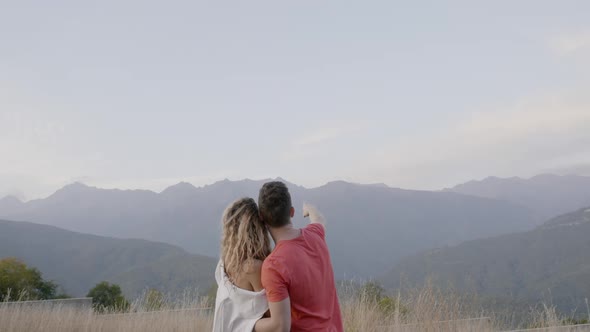 Excited Young Couple in Love Hug and Look at Beautiful Mountain View