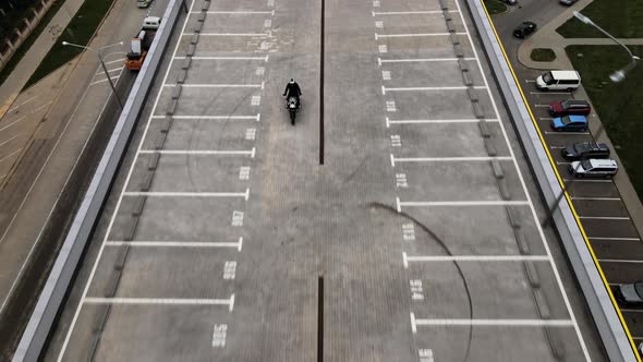 Man Riding Motorbike on Top of the Multilever Parking in City Filmed with Drone