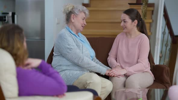 Happy Senior Grandmother Talking with Millennial Granddaughter Hugging As Blurred Adult Woman