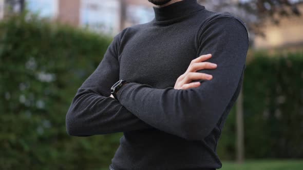 Unrecognizable Young Man with Crossed Hands Standing Outdoors on City Street