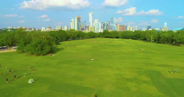 People playing sports in Zikler Park in Austin, Texas with the city skyscrapers in the background. D