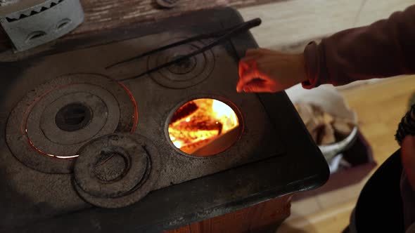 Woman In The House Putting Pieces Of Wood Into A Wood Stove