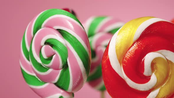 Round Twisted Caramel Lollipops Rotating on Pink Background