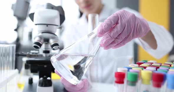 Scientist Holds Flask with Transparent Liquid Conducts Scientific Experiments