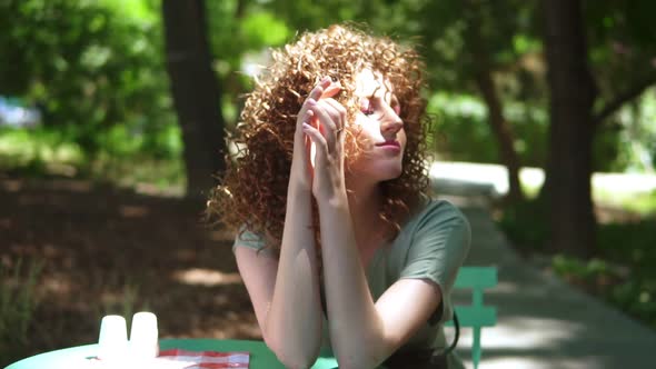 Portrait of Sensual Curly Ginger Girl Touching Her Red Hair in Summertime While Sitting in Outdoor