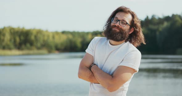 A Portrait of a Man with Long Hair and Beard Glasses on His Nose a Boy Puts Arms Crossed Looks Into