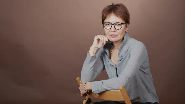 Studio Portrait of Mature Woman Sitting on Chair