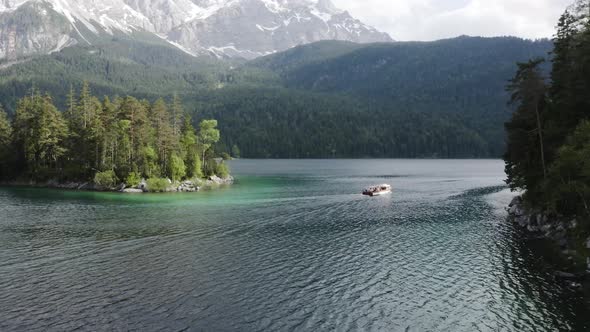 Following a boat on lake Eibsee from above during a sunny day
