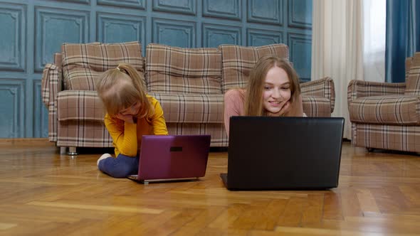 Woman Nanny and Child Girl Studying Together with Computer Laptop While Lying on Warm Floor at Home