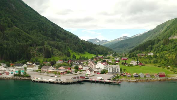 Waterfront Buildings Of Eidsdal Village With Birds Flying Over Fjord In Norway. - aerial