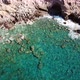 Aerial View of a Cave with Crystal Clear Waves at a Rocky Coast with Clear Blue Water - VideoHive Item for Sale