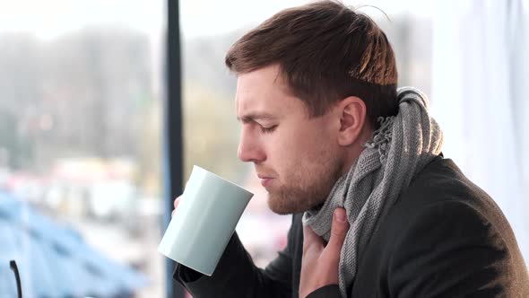 Sick Young Man Sitting on the Sofa Wrapped in Blanket