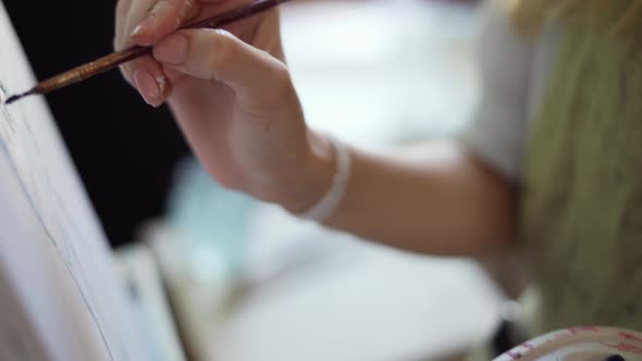 Close Up Woman Artist Painting Picture on Canvas in Art Studio Using Palette