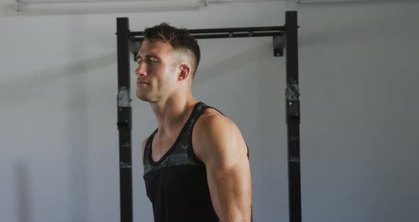 Fit smiling caucasian man turning to camera inside gym