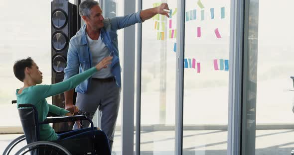 Caucasian Business people discussing over sticky notes on glass wall in the office 4k