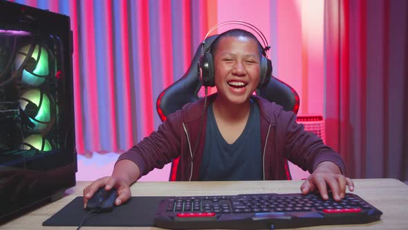 Asian Boy Wearing Headphones Playing Video Game, Laughing While Playing Video Game