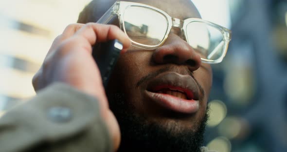 AfricanAmerican Man Uses a Mobile Phone Standing Near a Building in Evening