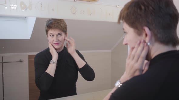 Shooting Over Shoulder of Reflection in Mirror of Charming Senior Brunette Lady. Caucasian Woman