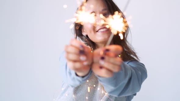Festive Mood with Sparklers. Attractive Girl in Pajamas with Sparklers and a Garland Waiting for the