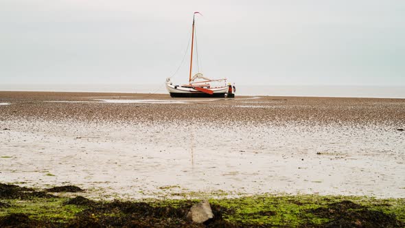 sailing boat dry on tidal mud flat at Dutch sea dike Wadden Sea timelapse