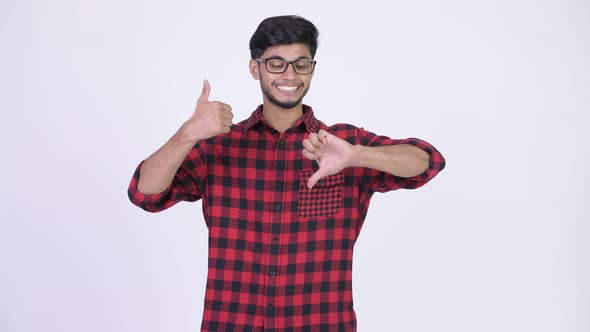 Young Confused Bearded Indian Hipster Man Choosing Between Thumbs Up and Thumbs Down