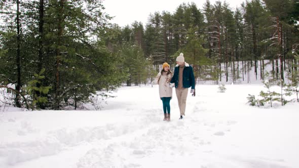 Happy Smiling Couple Walking in Winter Forest