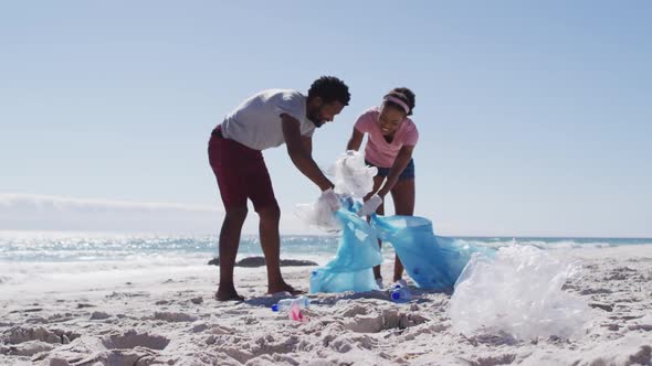 African american couple collecting plastic waste on the beach