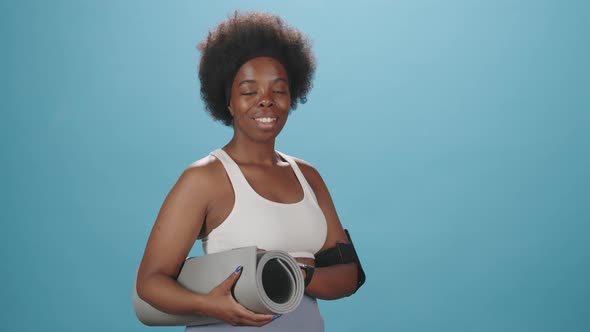 Portrait of Curvy Black Woman in Sportswear with Yoga Mat