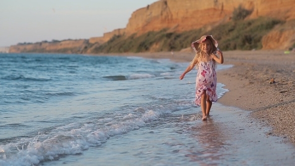 Little Girl In Sundress And Hat Running Along The