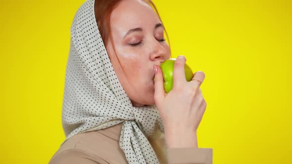 Headshot of Beautiful Young Redhead Woman with Green Eyes Eating Healthful Juicy Apple in Slow