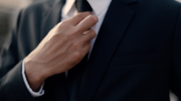 Asian businessman getting dressed in a black suit preparing for work.