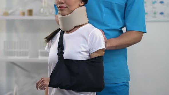 Therapist Applying Smiling Female Patient in Foam Cervical Collar Arm Sling