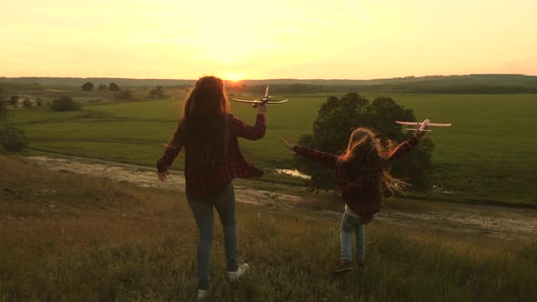 Dreams of Flying. Happy Childhood Concept. Two Girls Play with a Toy Plane at Sunset. Children on