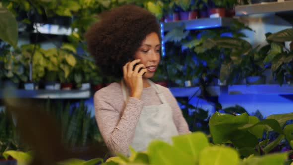African woman florist talking by phone