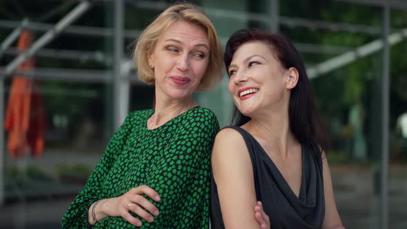 Side View Two Confident Women Standing Back to Back with Crossed Hands Smiling Talking in Slow