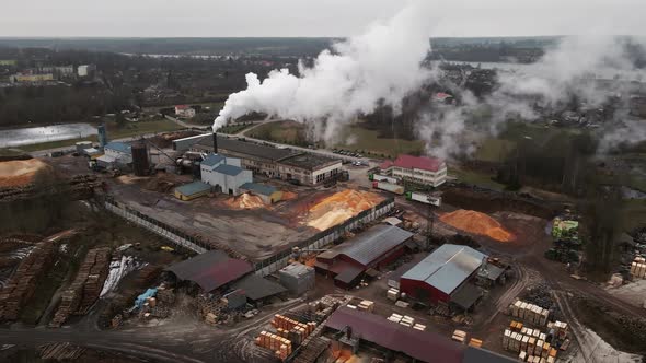 Ascending Shot of Operating Log Sawmill Factory with Large Chimney Emitting Smoke Aerial