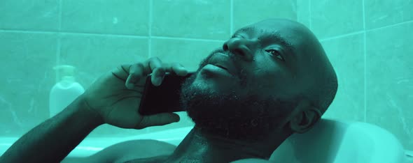 Black Man Chatting on Phone in Bath