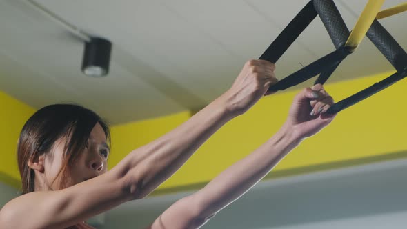 Asian young sportswoman exercising workout on TRX exercise rope at fitness stadium or gym club.