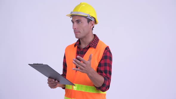 Young Happy Hispanic Man Construction Worker Talking While Reading on Clipboard