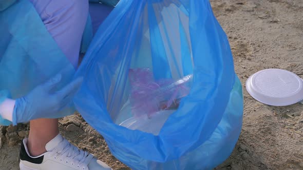 Closeup of a Young Activist Girl in a Gloves Collects Garbage on the Beach