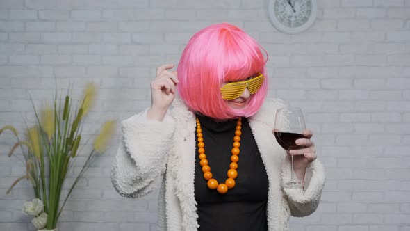  woman with pink hair dancing with glass of wine in hand celebrating success