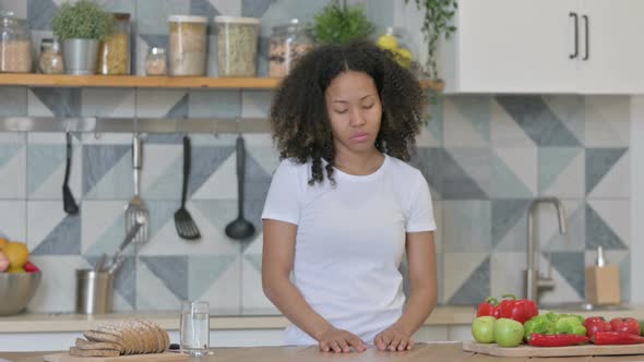 Young African Woman Feeling Worried While Standing in Kitchen