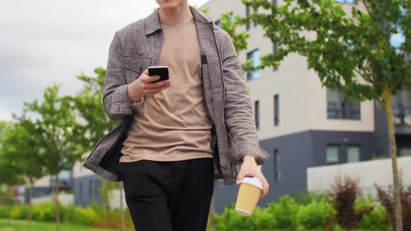 Young Man with Smartphone Drinking Coffee in City