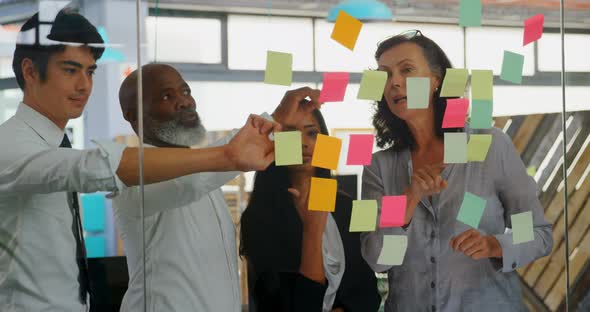 Executives discussing over sticky note on glass wall 4k